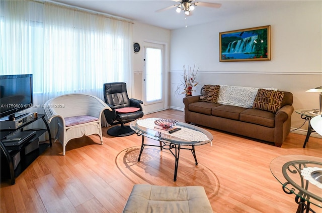 living area featuring wood finished floors, baseboards, and ceiling fan