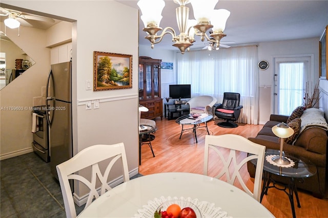 dining area featuring wood finished floors and ceiling fan with notable chandelier