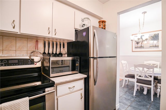 kitchen with stainless steel appliances, light countertops, white cabinets, tile patterned floors, and a chandelier