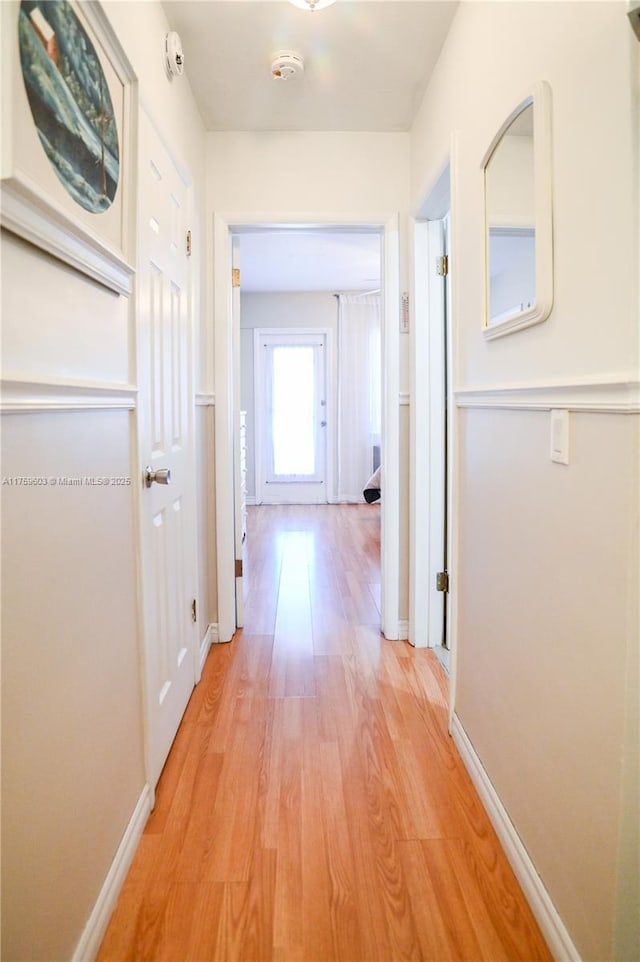 hallway with light wood-style flooring and baseboards