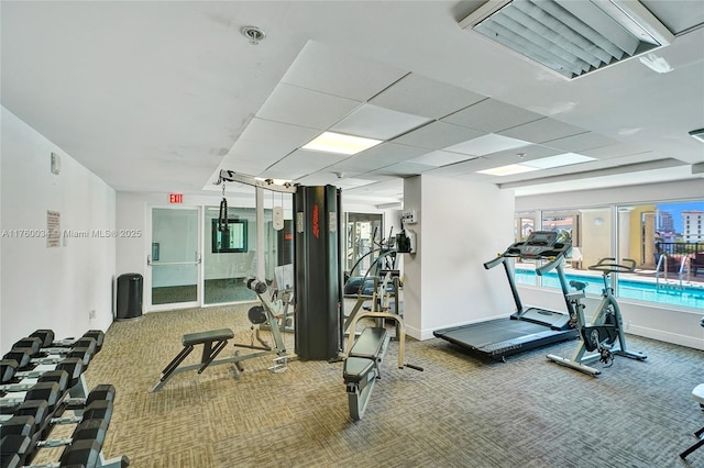 gym with visible vents, a paneled ceiling, baseboards, and carpet floors