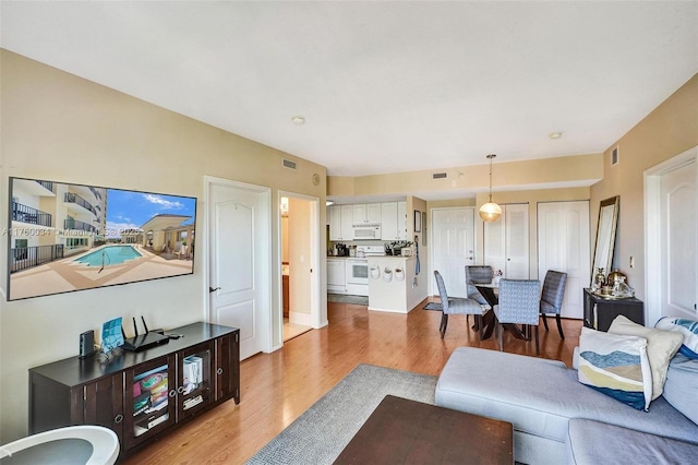 living area featuring light wood-style flooring and visible vents