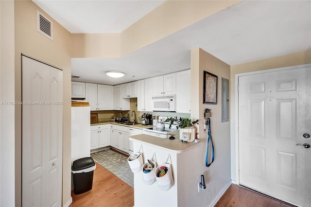 kitchen with white appliances, visible vents, light wood-style flooring, electric panel, and a sink