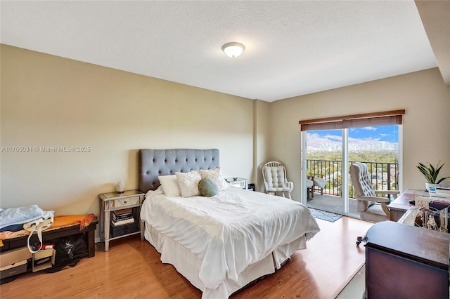 bedroom featuring a textured ceiling, access to exterior, and light wood finished floors