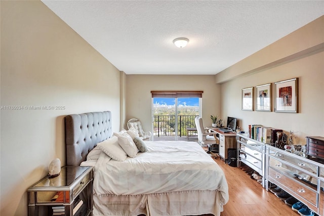 bedroom with a textured ceiling, light wood-style flooring, and access to outside