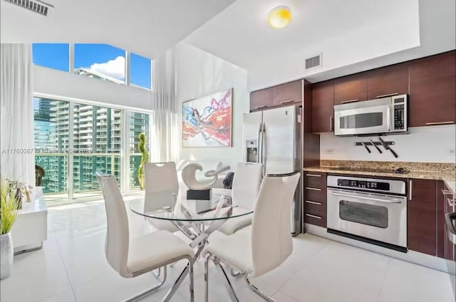 kitchen with light tile patterned floors, visible vents, stainless steel appliances, and light stone counters