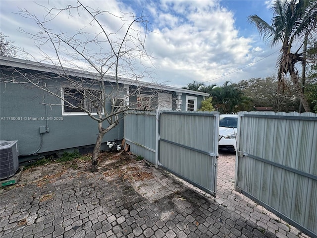 view of side of home with central air condition unit and fence