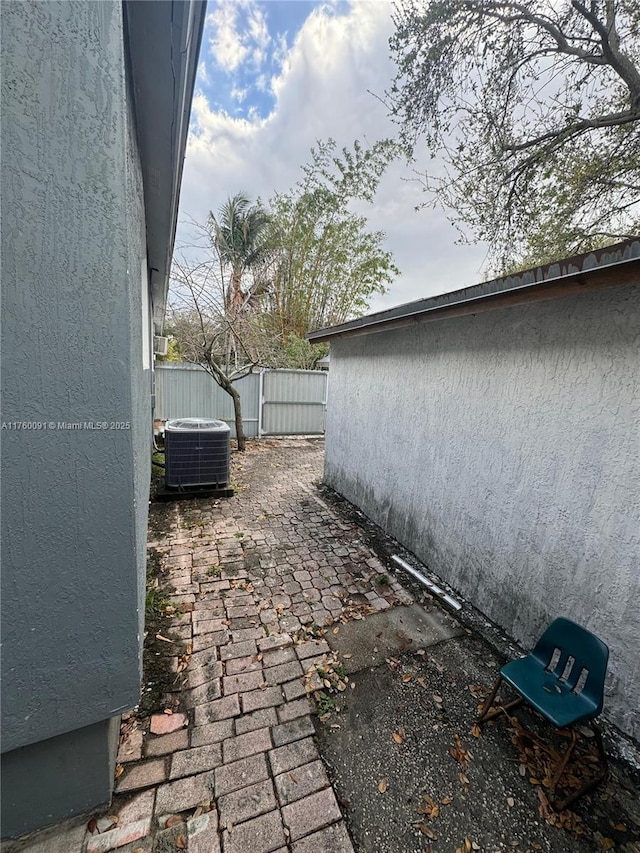 exterior space featuring a patio area, central AC unit, fence, and stucco siding