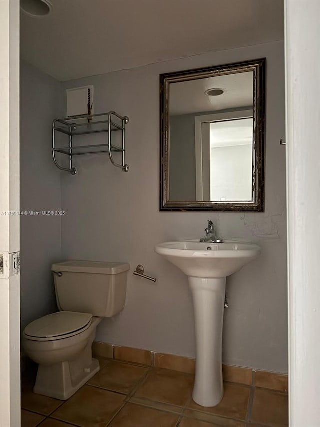 bathroom with tile patterned flooring, toilet, and baseboards