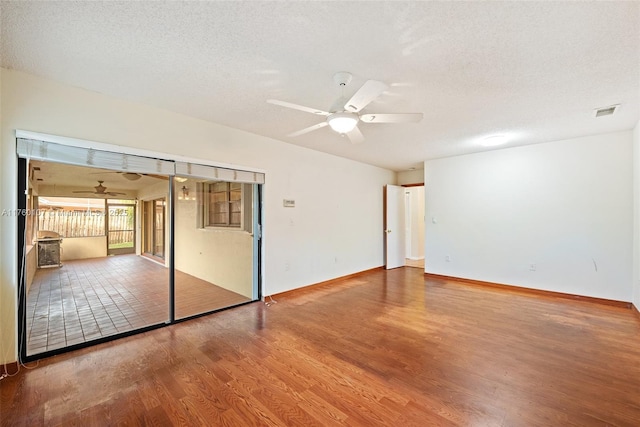 spare room featuring ceiling fan, visible vents, a textured ceiling, and wood finished floors