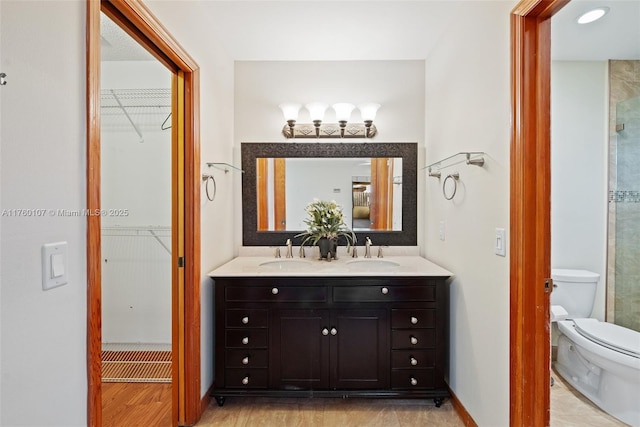 bathroom with a sink, toilet, and a spacious closet