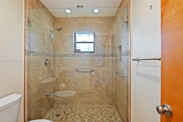 bathroom featuring toilet and a shower stall