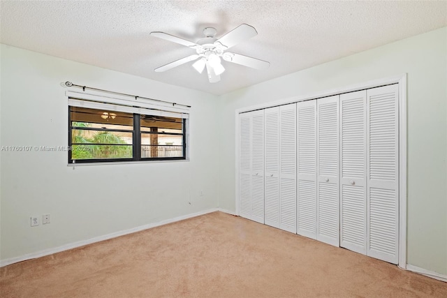 unfurnished bedroom featuring ceiling fan, carpet flooring, a closet, and a textured ceiling