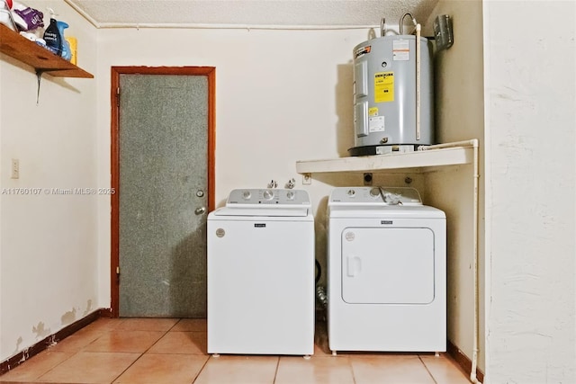 laundry area with electric water heater, baseboards, washing machine and dryer, light tile patterned floors, and laundry area