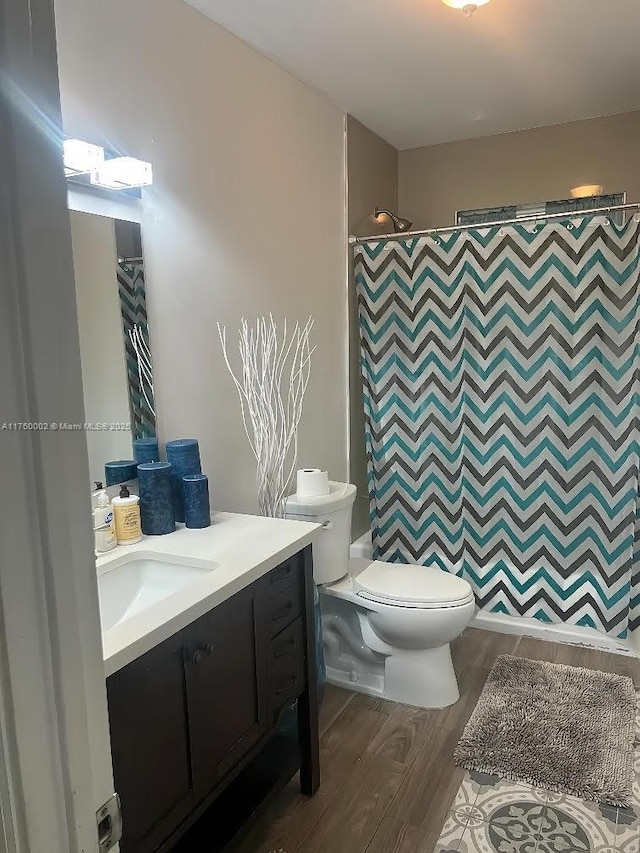 full bathroom featuring vanity, a shower with shower curtain, toilet, and wood finished floors