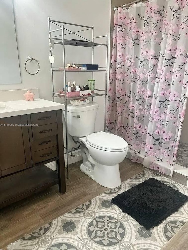 full bath with a shower with shower curtain, toilet, wood finished floors, and vanity