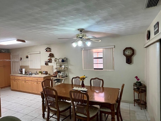 dining space featuring light tile patterned floors, visible vents, a textured ceiling, and ceiling fan