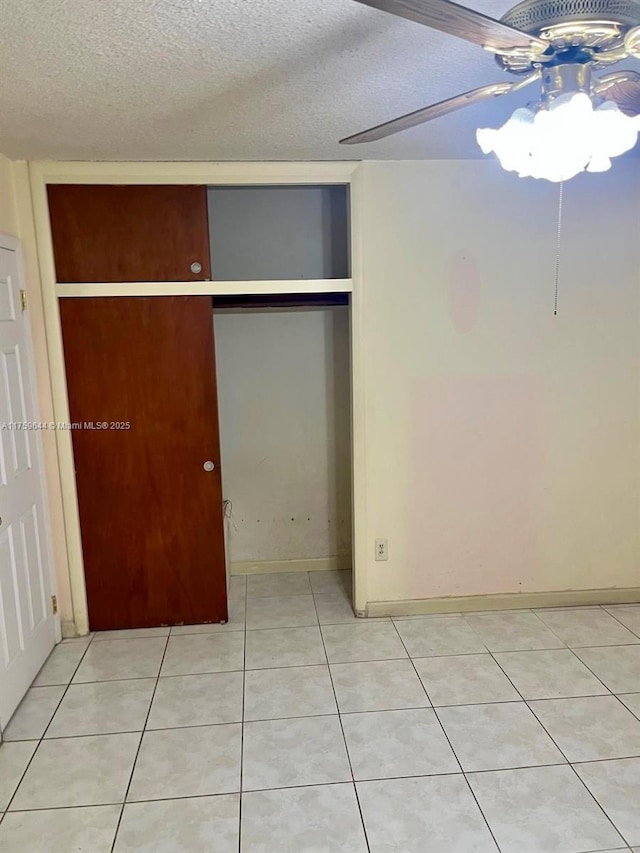 unfurnished bedroom featuring light tile patterned floors, a ceiling fan, a closet, and a textured ceiling