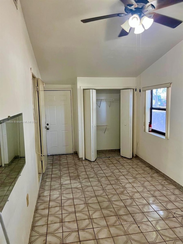 unfurnished bedroom featuring a closet, lofted ceiling, light floors, and a ceiling fan