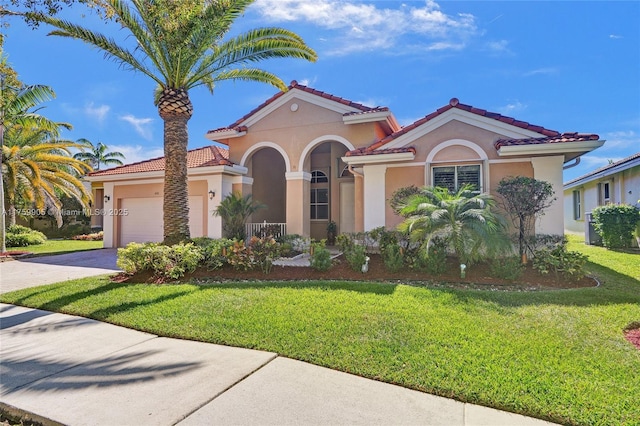 mediterranean / spanish house with stucco siding, an attached garage, driveway, and a front lawn