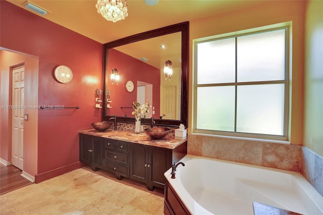 bathroom with double vanity, a bath, visible vents, and a sink