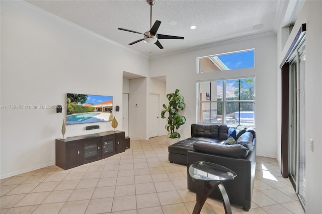 living room featuring baseboards, light tile patterned flooring, ceiling fan, ornamental molding, and a textured ceiling