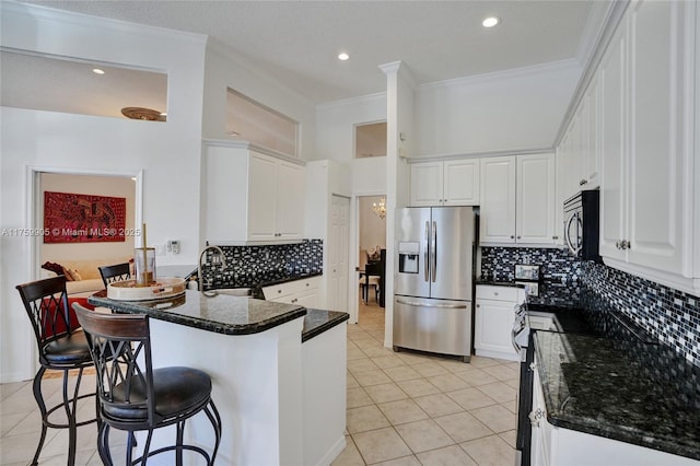 kitchen with light tile patterned floors, white cabinets, a peninsula, and stainless steel appliances