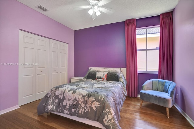 bedroom with visible vents, baseboards, a textured ceiling, and wood finished floors