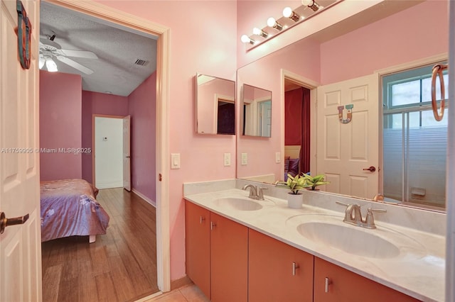 ensuite bathroom featuring double vanity, connected bathroom, visible vents, and a sink