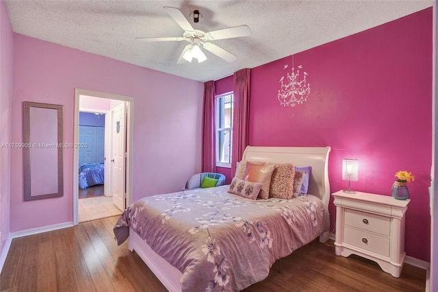 bedroom with a textured ceiling, a ceiling fan, baseboards, and wood finished floors