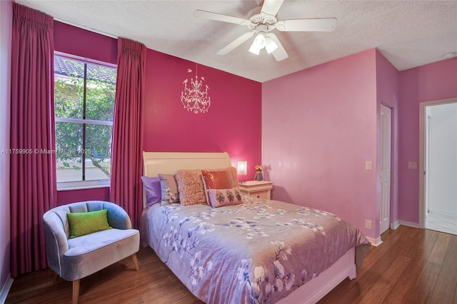 bedroom with a textured ceiling, a ceiling fan, baseboards, and wood finished floors