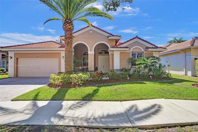 mediterranean / spanish home with a front yard, decorative driveway, a garage, and stucco siding