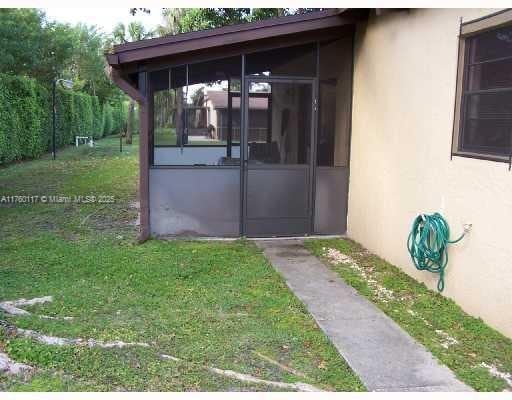 view of side of home with stucco siding, a lawn, and a sunroom