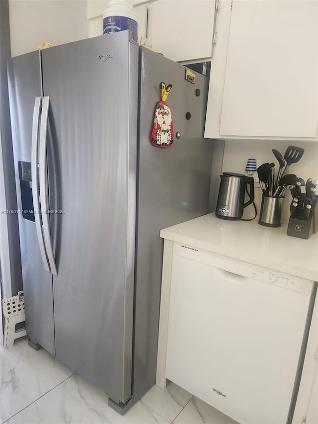 kitchen with white cabinetry, stainless steel fridge, light countertops, and marble finish floor