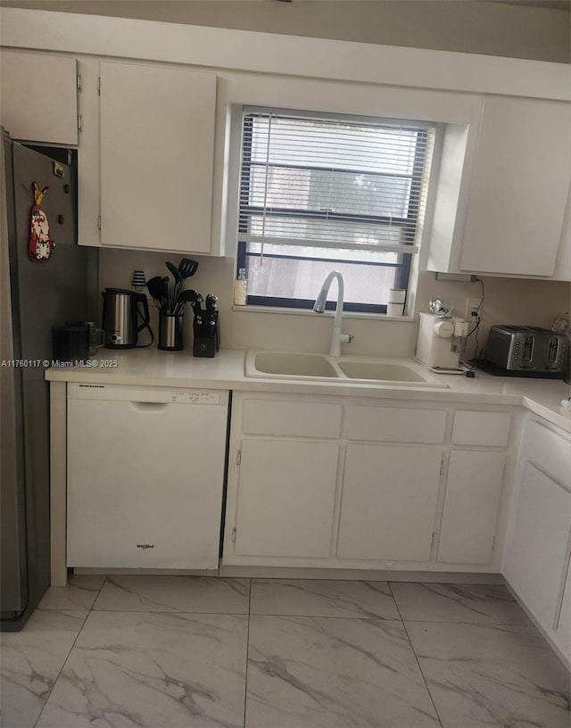 kitchen featuring marble finish floor, a sink, white cabinetry, freestanding refrigerator, and dishwasher