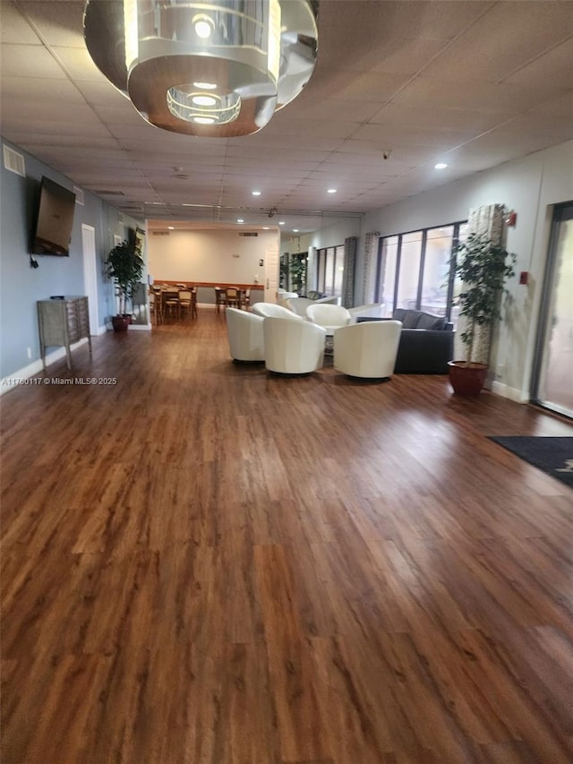 unfurnished living room featuring wood finished floors, baseboards, and a drop ceiling