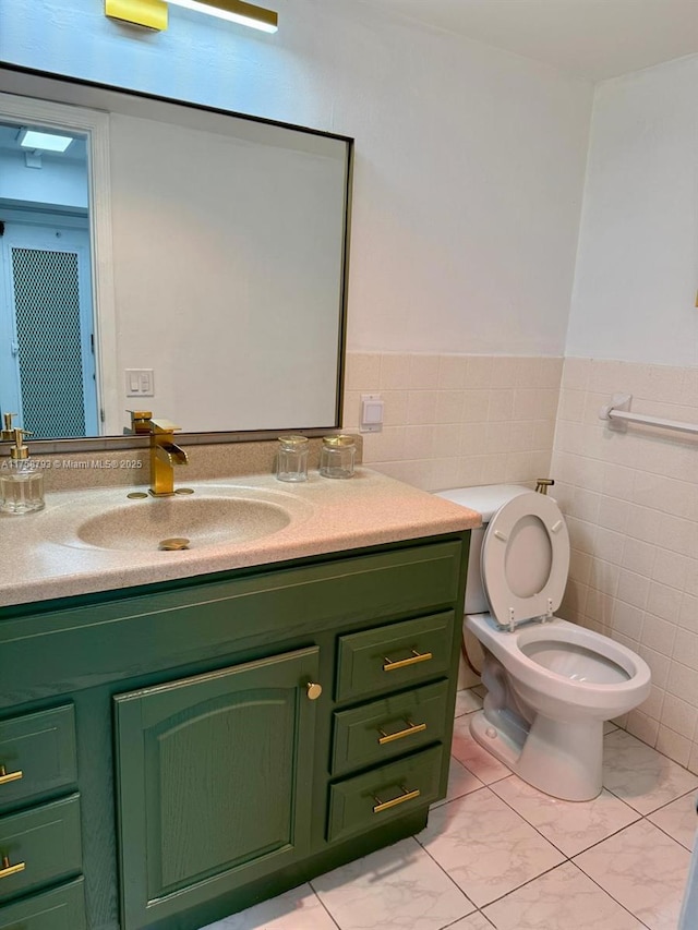 half bathroom with wainscoting, toilet, tile walls, and vanity