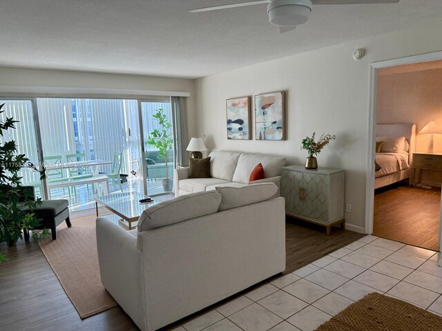 living room with a textured ceiling, light wood-style flooring, and a ceiling fan