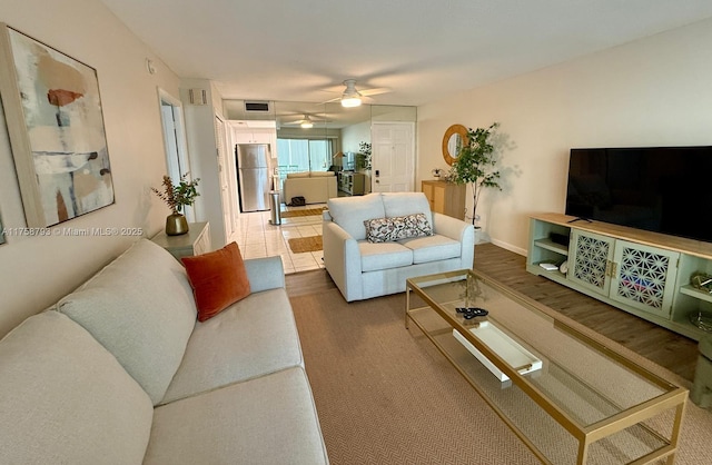 living area with a ceiling fan, visible vents, and baseboards