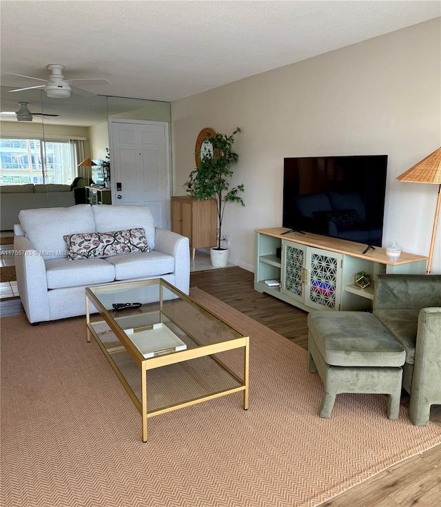 living area with a ceiling fan and wood finished floors