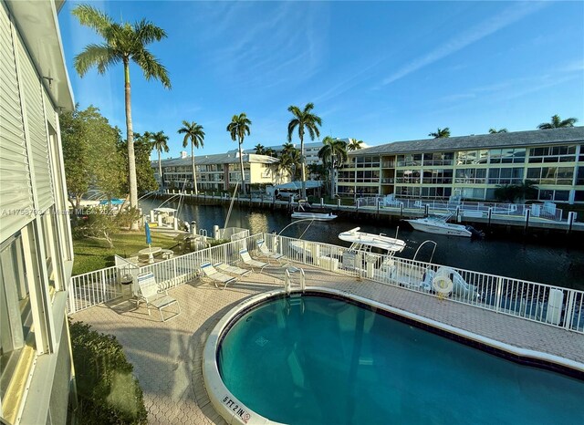 community pool featuring a water view and fence