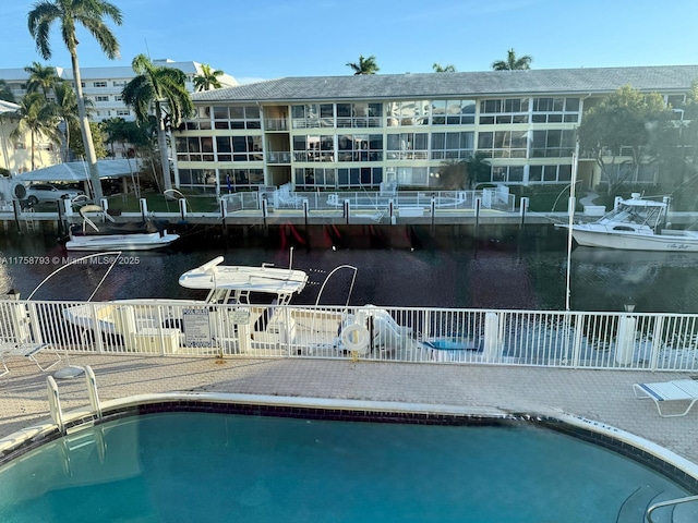 community pool featuring a water view and fence