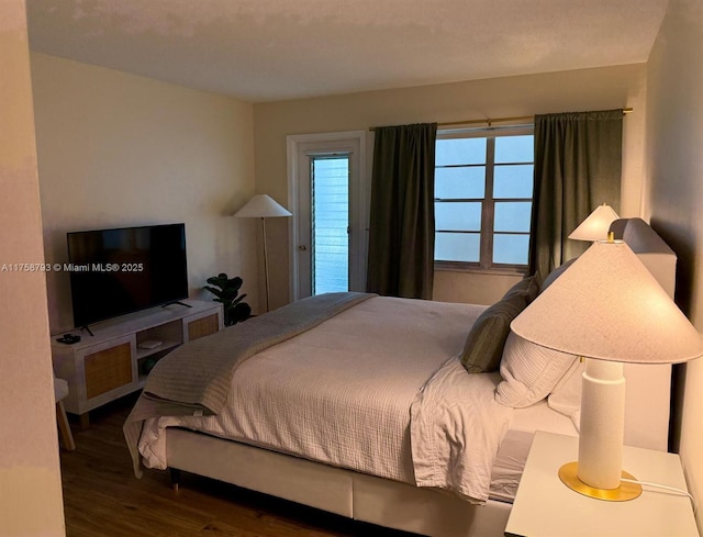 bedroom with access to outside and wood finished floors