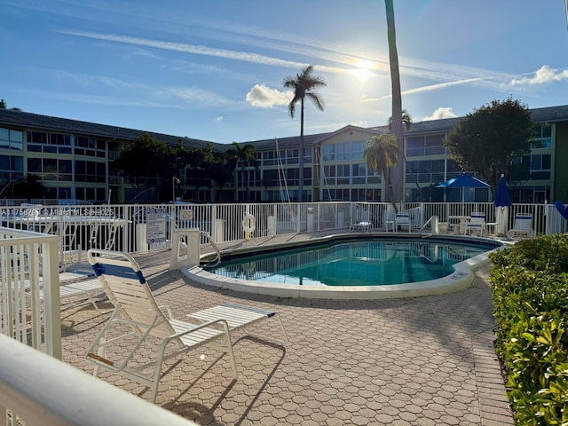 community pool with a patio and fence