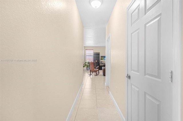 hall with light tile patterned flooring and baseboards