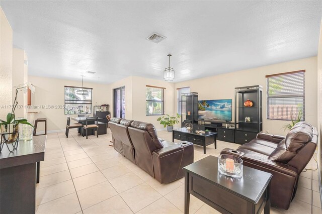 living room with light tile patterned flooring, baseboards, visible vents, and a wealth of natural light
