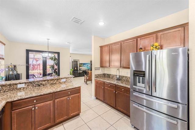 kitchen featuring light tile patterned floors, decorative light fixtures, stainless steel fridge, and light stone counters
