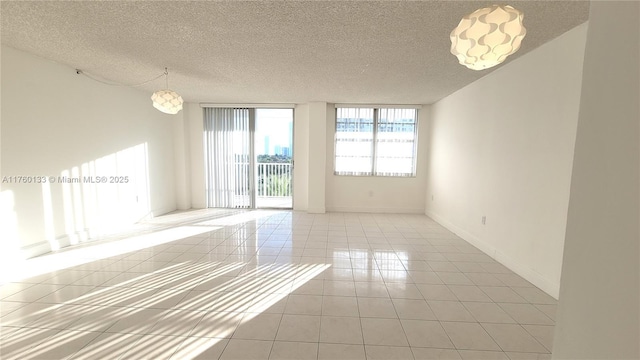 tiled empty room featuring baseboards and a textured ceiling