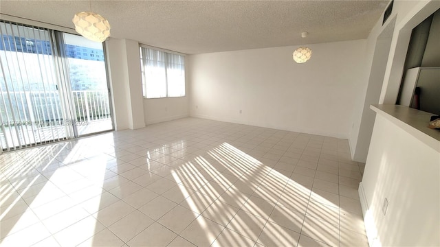 spare room with light tile patterned floors, visible vents, a textured ceiling, and baseboards