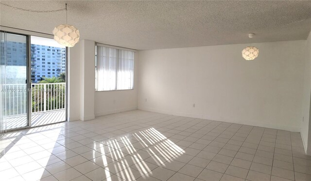 empty room featuring light tile patterned floors, a textured ceiling, and baseboards